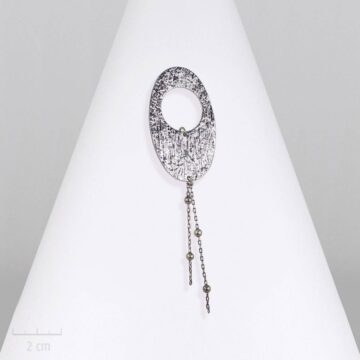 Broche ovale, moderne gravée, astre strié de lumière, symbole céleste et futuriste. Style urbain, chargé d'énergie, argent. Création fantaisie ZOR