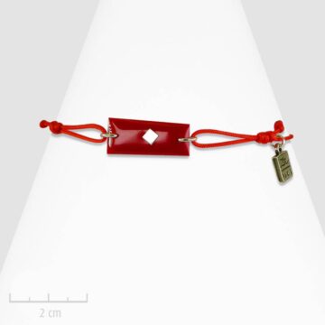 Bracelet lacet en drapeau rouge pour enfant. Bijou plaque rectangle à carreau, symbole de la tribu des Red Arlequin de TRH. Création Zor
